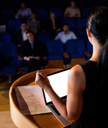 rear-view-female-business-executive-giving-speech
