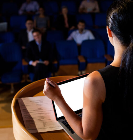 rear-view-female-business-executive-giving-speech